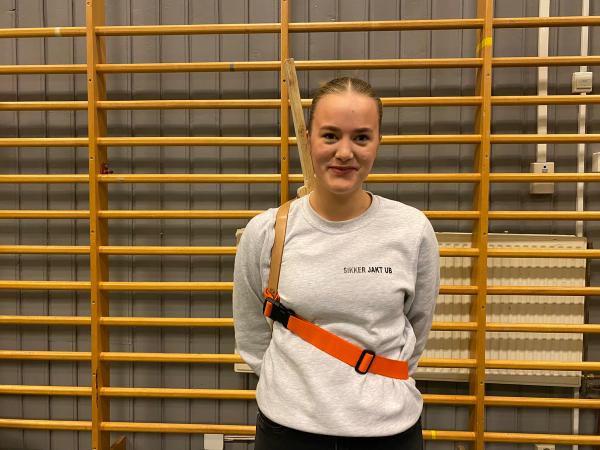 Elev viser fram produktet forfra. Våpen spent fast med stropp.