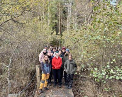 Mange elever i friluftsliv-klær oppstilt på en liten bro.