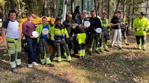 Elever i arbeidstøy står foran en liten traktor.