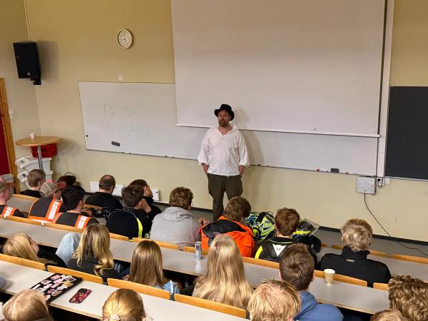 En mann snakker til elever i et klasserom - kledd som en bonde fra 1800-tallet.