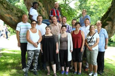 Kvinner og menn ved et tre i parken en sommerdag.