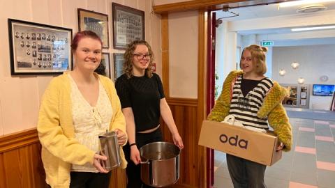 Lærer og to elever bærer inn maten