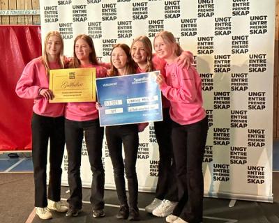 Fem jenter i rosa gensere med diplom og gavesjekk.