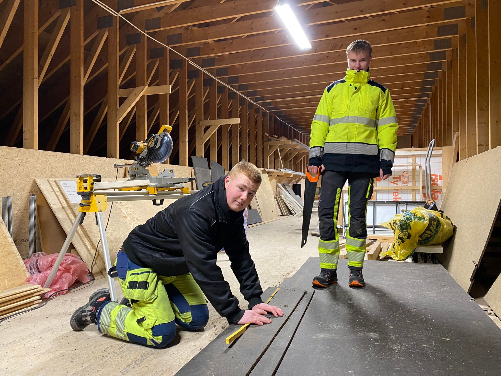 To elever skjærer til rett størrelse av plater som skal snekres på vegg.