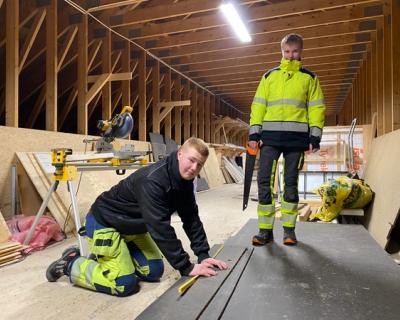 To elever skjærer til rett størrelse av plater som skal snekres på vegg.