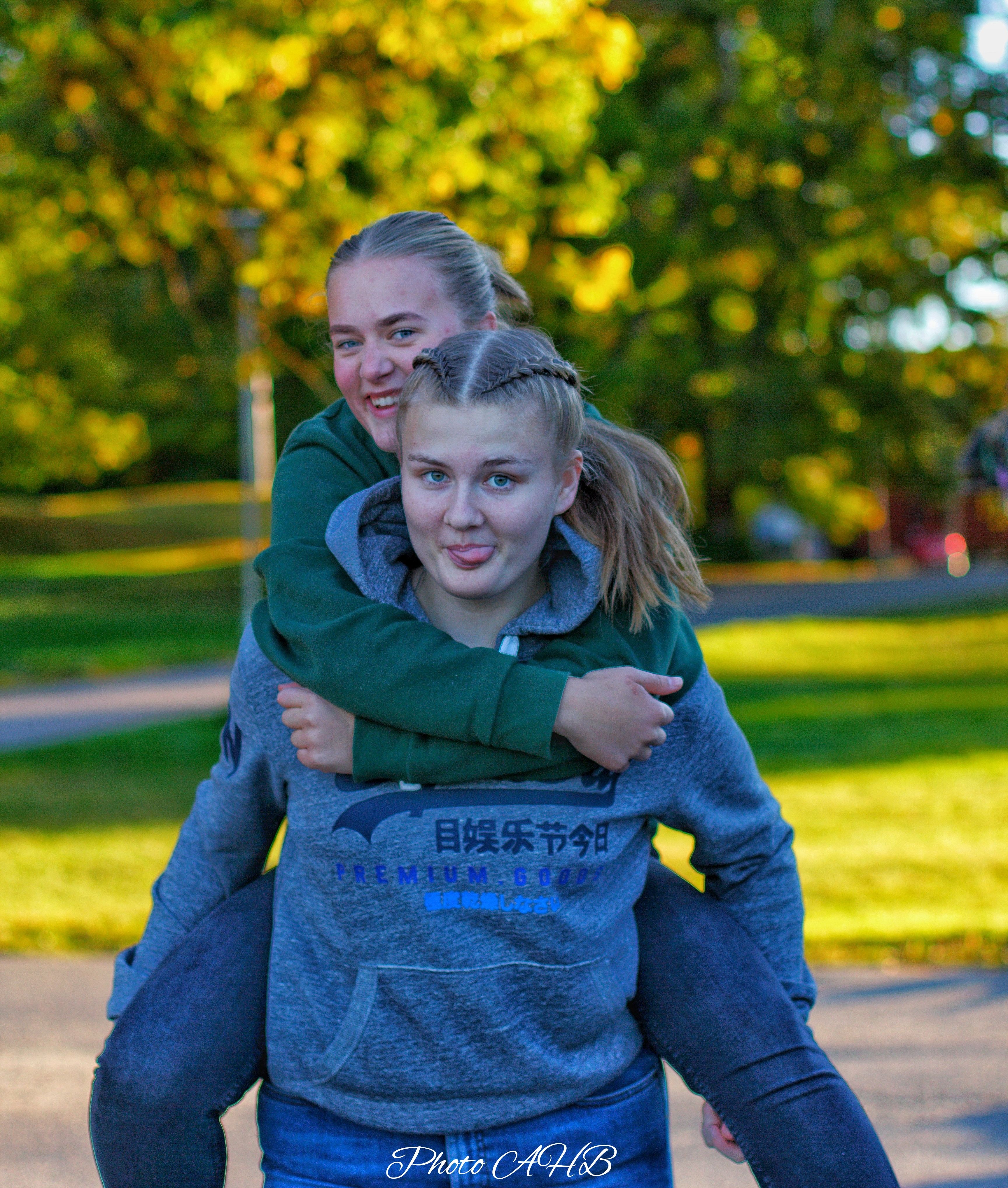 Ei jente sitter på ryggen til ei annen jente.