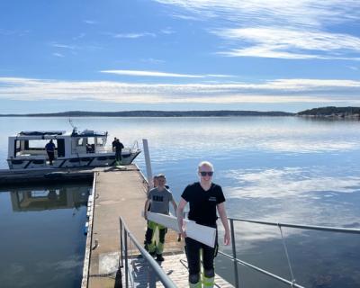 To elever bærer materialer fra en båt til fastland.