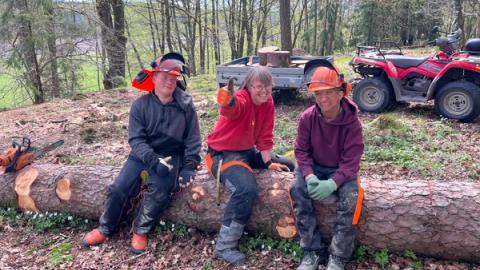 Tre mennesker sitter på en stokk.