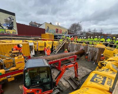 Et anleggsområde med boremaskin. Elever følger med på hva som skjer.