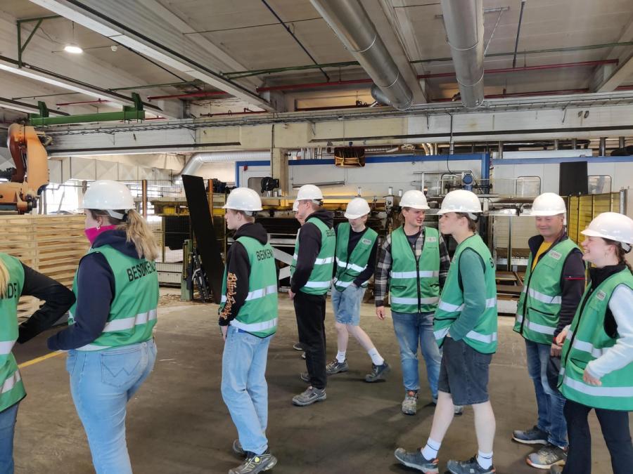 Elever inne i en fabrikk. Alle går med hjelm.