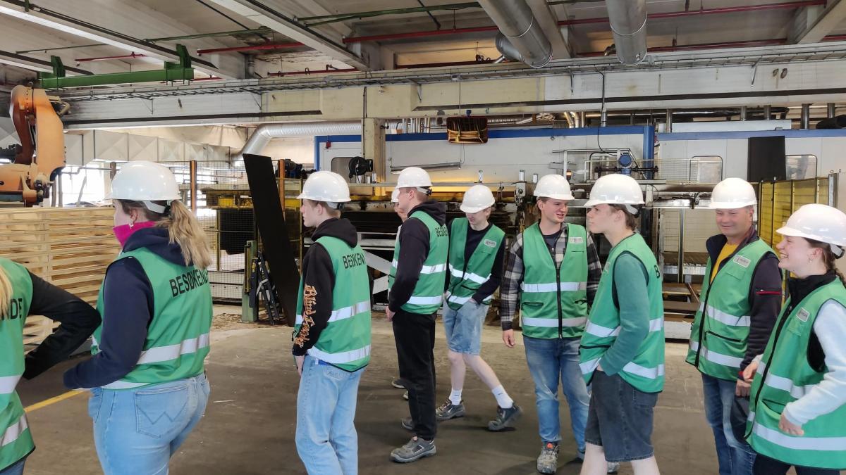 Elever inne i en fabrikk. Alle går med hjelm.