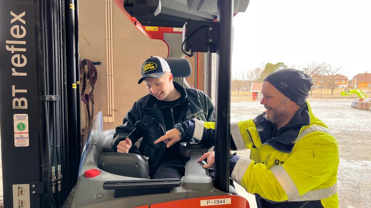 Lærer viser en elev hvordan man styrer trucken.