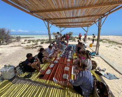 Elever sitter i skyggen på ei matte