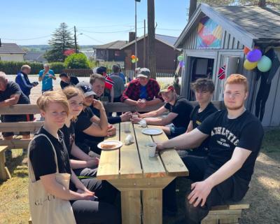 Tombelever sitter ved krakk og spiser kake