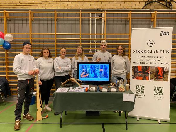 Seks ungdommer på stand. Hvite gensere, svarte bukser. 