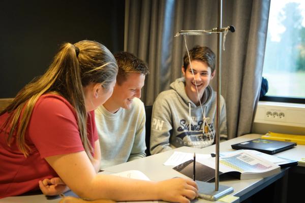 Tre elever sitter og studerer i klasserommet