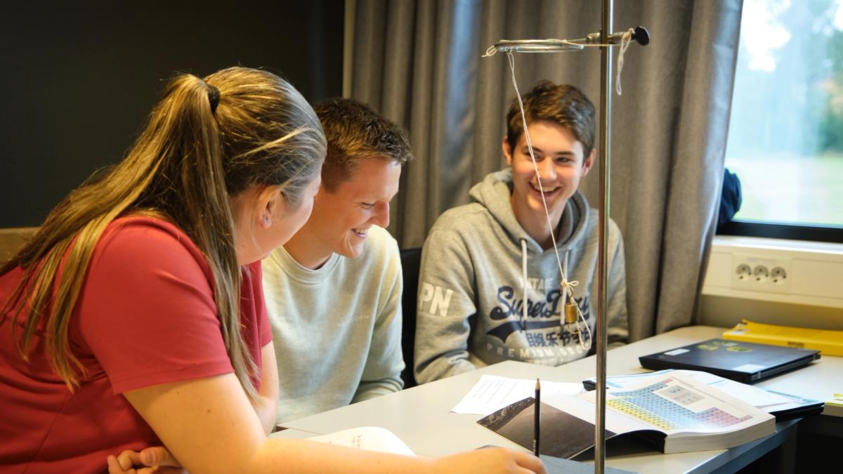 Tre elever sitter og studerer i klasserommet