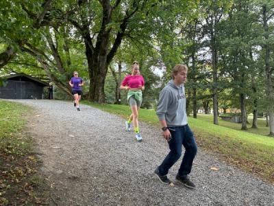 Tre elever som løper på en sti i en park.