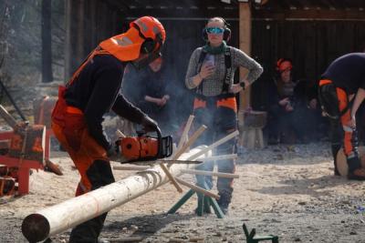 Elev trener kvisting med motorsag. Elev bakenfor filmer og tar tiden,