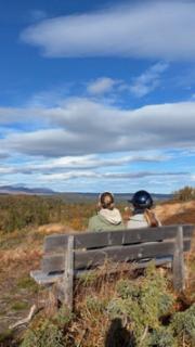 To elever sitter på en krakk i fjellet. Flotte høstfarger.