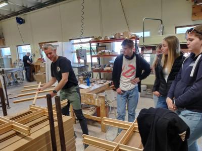 En arbeider i et fabrikk-lokale forklarer om tresprosser som lages.