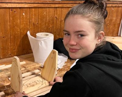 Jente som smiler, har et prosjekt i snekkerverkstedet.