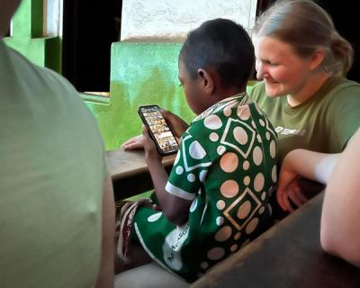 En smilende elev som viser et barn på telefonen sin.