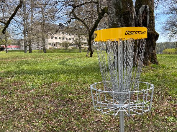 Bilde av kurv til diskgolf, parkfløya i bakgrunnen. 