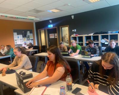 Elever i klasserom sitter og jobber.