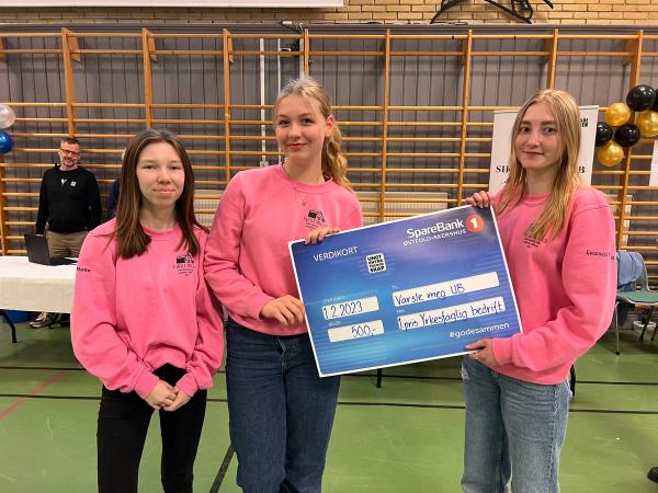 Tre jenter i rosa gensere med sjekk fra sparebank 1.