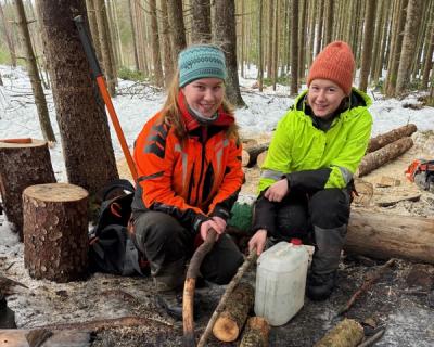 To elever sitter ved bålet.