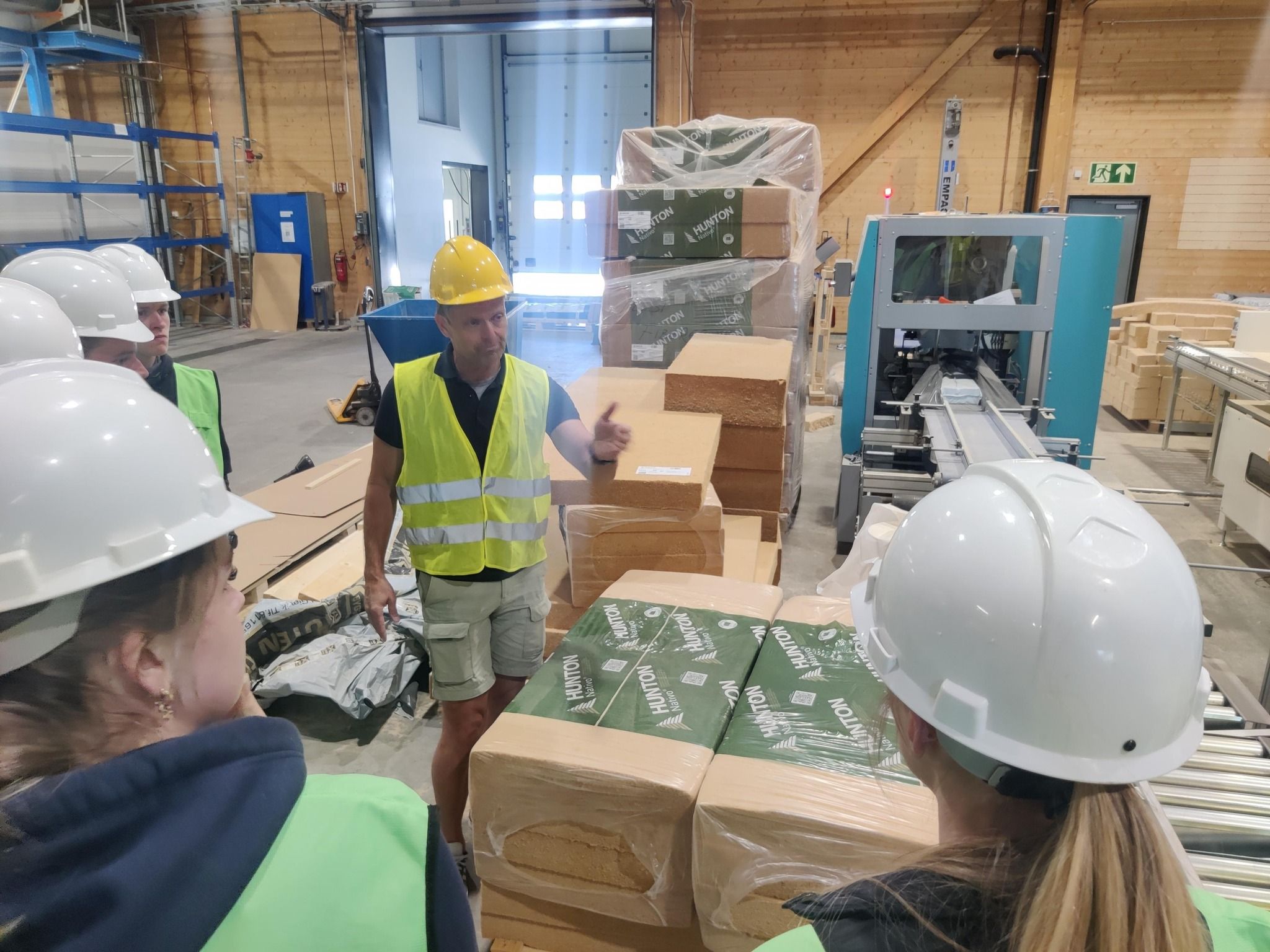 I et fabrikkområde hvor en arbeider informerer elever om produkter som lages, her isolasjonsmatter av trefiber.