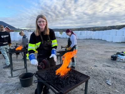 Jente som ser inn i kamera, ild foran seg.