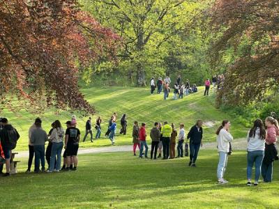 Elever står i grupper i parken. 