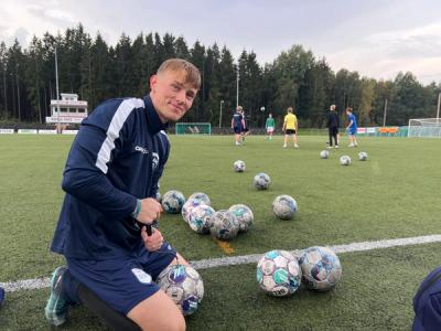 Fotballtrener på sidelinjen på en fortballbane, hvor han pumper luft i fotballer.