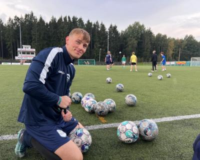 Fotballtrener på sidelinjen på en fortballbane, hvor han pumper luft i fotballer.