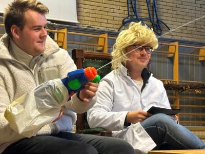 Utkledte elever på ei scene. den en bruker vannpistol.