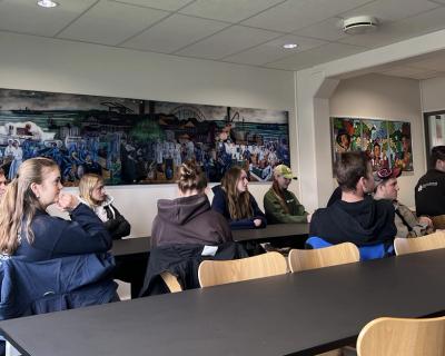 Elever sitter i et konferanserom.