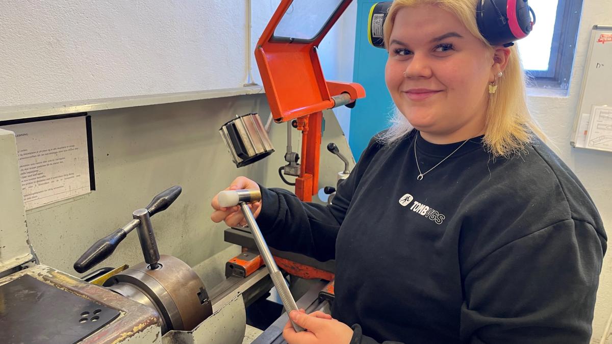 Jente-elev med en stålhammer i hånden.