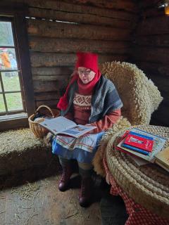 Nissemor sitter i en godstol og leser fra en bok.