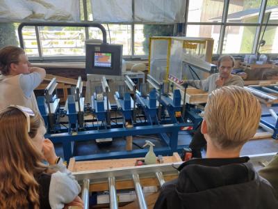 En arbeider gir informasjon til tre elever i et fabrikklokale.