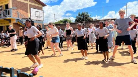 Elevene danser med lokale elever på en skole