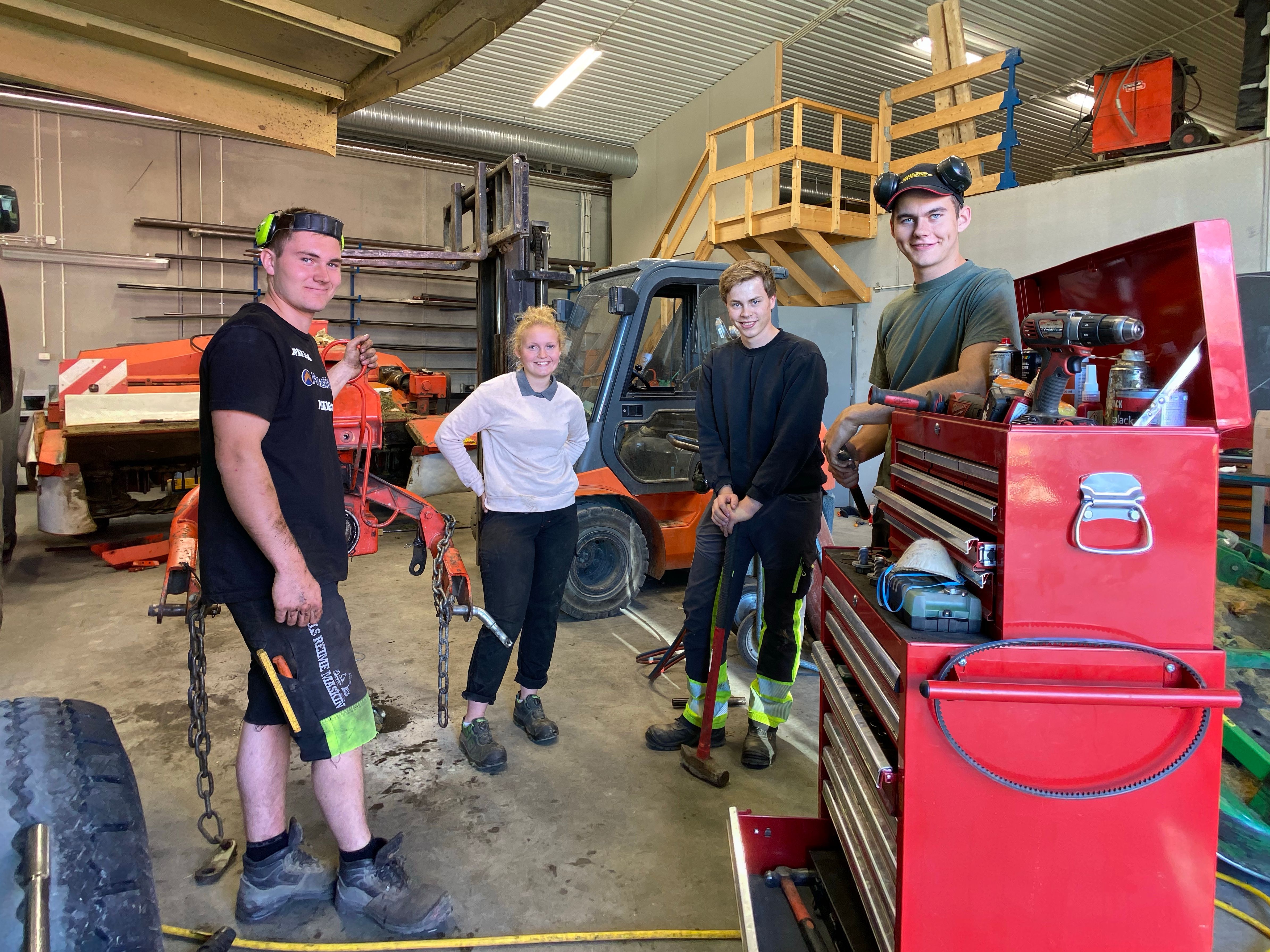Fire elever i verkstedhall.