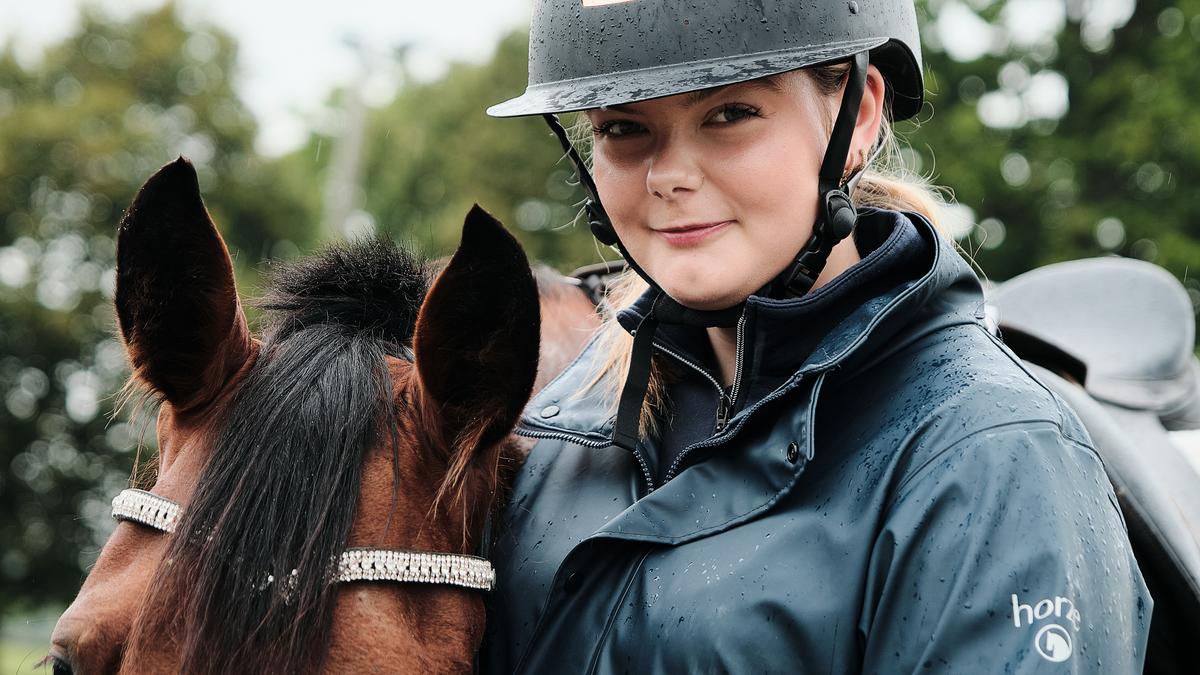 To elever rir hver sin hest på ridebane.