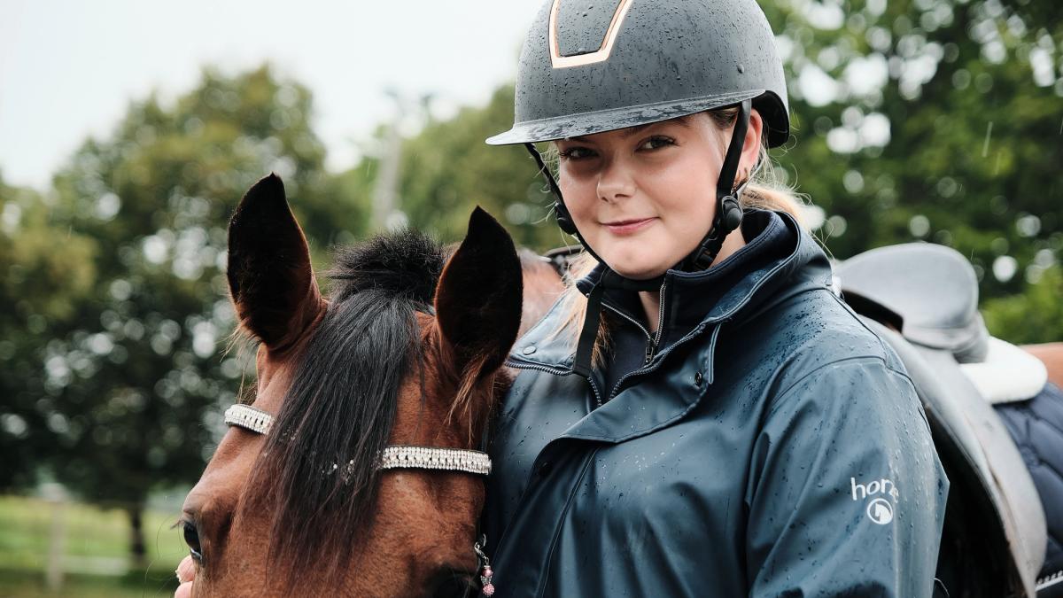 To elever rir hver sin hest på ridebane.