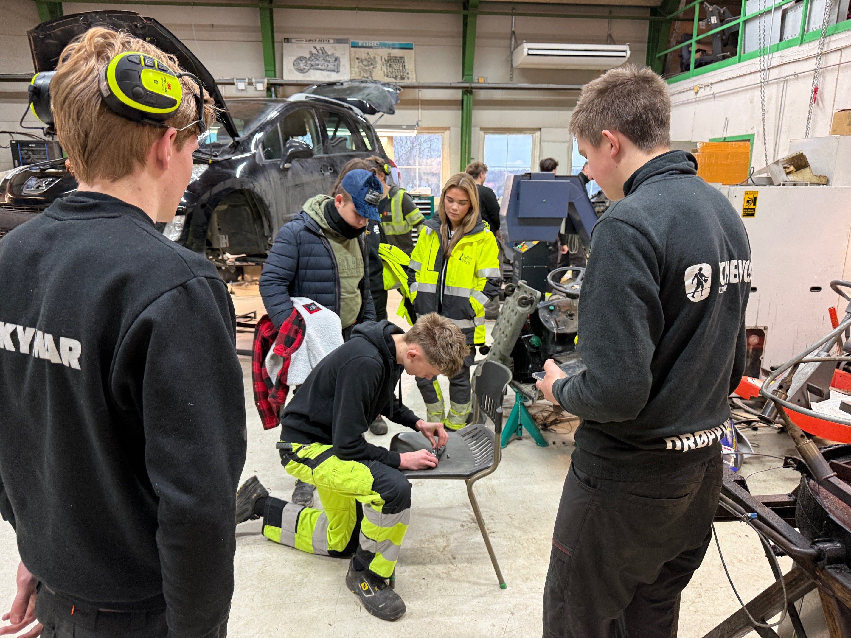 Elever følger med på en som utfører en reparasjon i en kjøretøyhall.