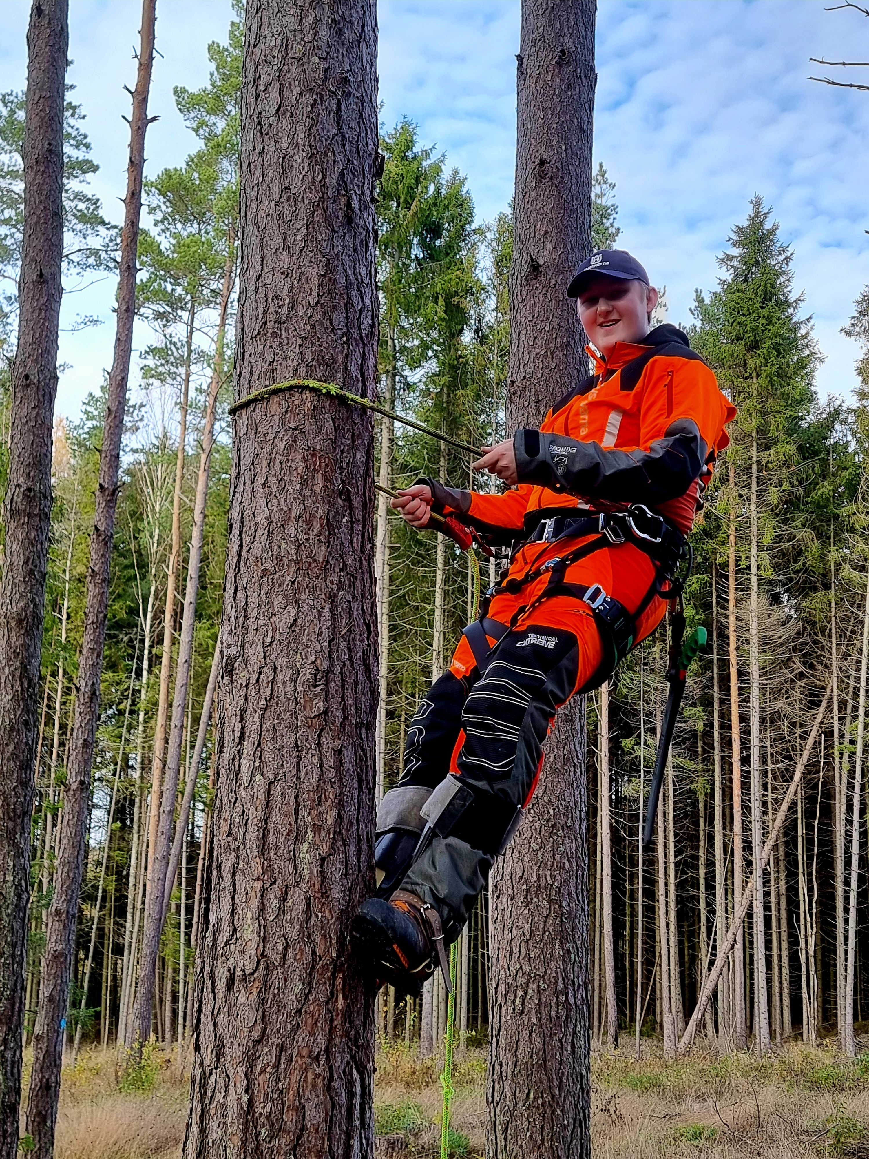 Elev som klatrer i skogbruk.
