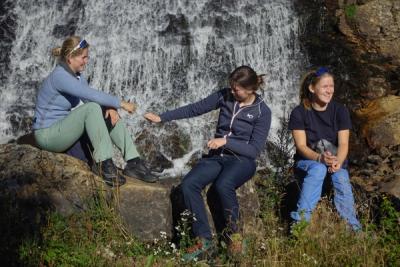Tre elever sitter ved en foss.