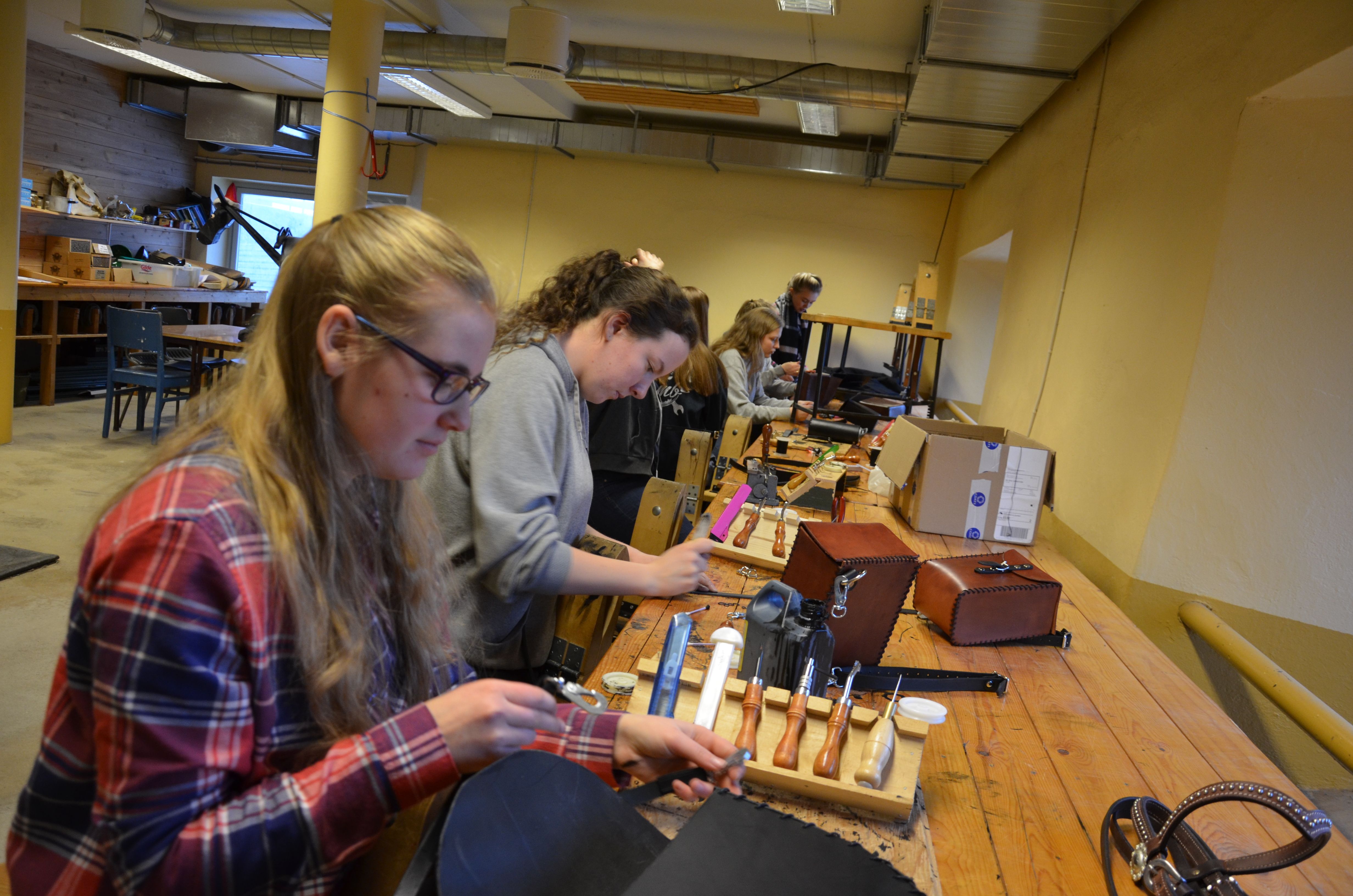 Elever syr hesteutstyr i lærarbeid ved en arbeidsbenk.