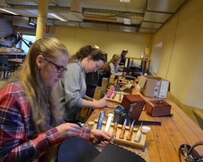 Elever syr hesteutstyr i lærarbeid ved en arbeidsbenk.